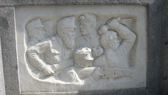 Bassorilievo posto alla base della stele in cime alla scalinata del cimitero monumentale. Al centro si può notare il colonnello Spiegel, capo delle operazioni in Giudicarie